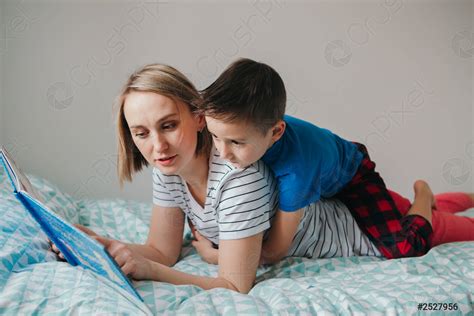 Happy Caucasian Mother And Son Family Reading Book In Bedroom Stock