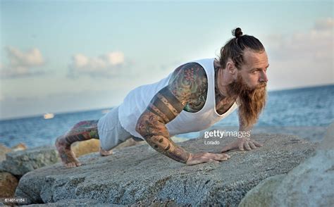 Tattooed Bearded Handsome Male Stretching Before A Daytime Seafront