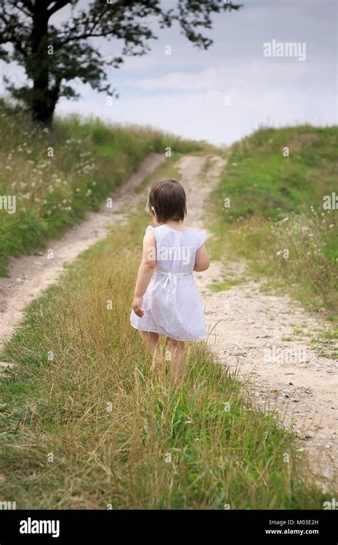 Little Girl Walks Barefoot Along The Road White Dress And Barefoot Road