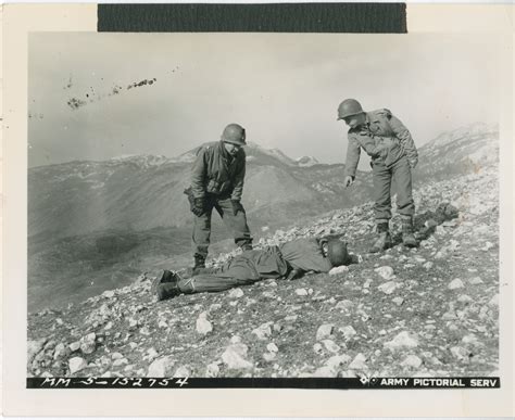 Us Soldiers Examine A Deceased German Soldier Lying On A Rocky Hillside
