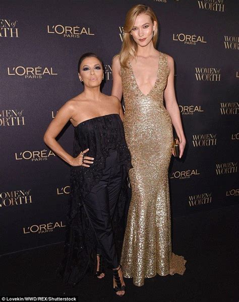 Two Women Standing Next To Each Other On A Red Carpet