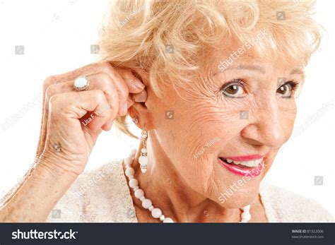 Closeup Of A Senior Woman Inserting A Hearing Aid In Her Hear Focus On The Hearing Aid Stock