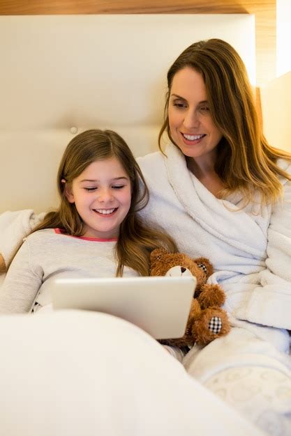free photo mother and daughter using digital tablet in bedroom