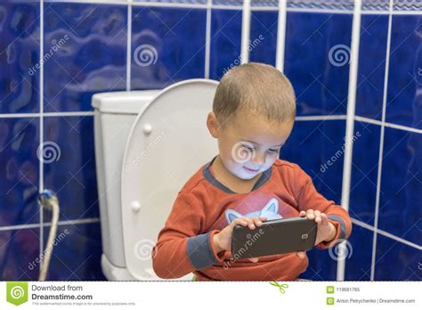 Inklusive spülung in die kanalisation versenkt hat. Kleiner Junge, Der Zu Hause Auf Der Toilette Im Badezimmer Mit Der Anwendung Eines Smartphone ...