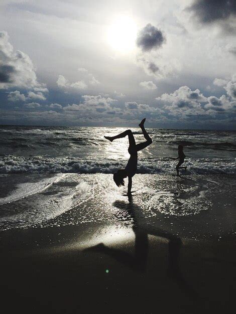 Premium Photo Silhouette Person Doing Handstand On Beach Against Sky