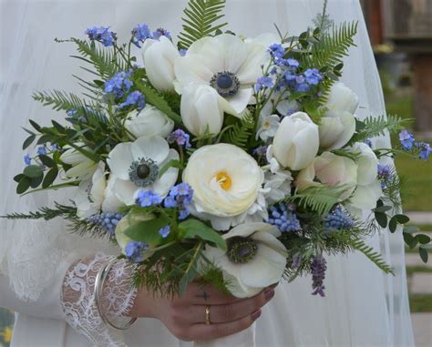 A Bride Holding A Bouquet Of White And Blue Flowers