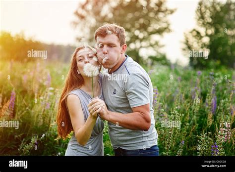 Young Happy Couple Blowing Together Dandelions Outdoor In Nature Stock
