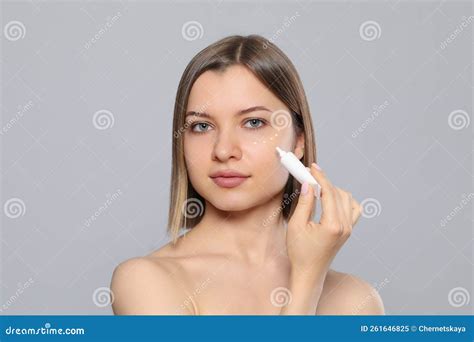 Young Woman Applying Cream Under Eyes On Light Grey Background Stock Image Image Of Girl