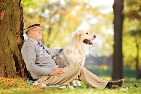 Senior Gentleman And His Dog Sitting On Ground Stock Photos