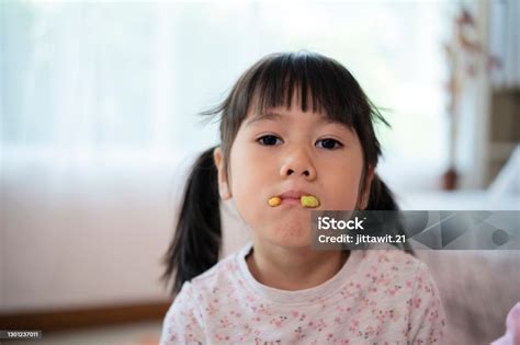 An Asian Girl Uses Her Mouth To Hold The Biscuits Playing As The Fangs
