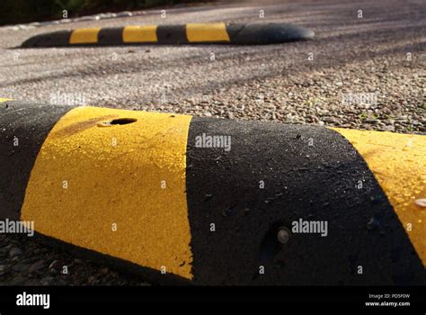 Black And Yellow Speed Bumps In The Sun With Wet Surface Stock Photo