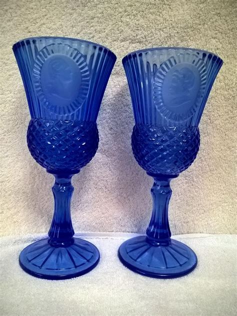 Two Blue Glass Goblets Sitting Next To Each Other On Top Of A Table