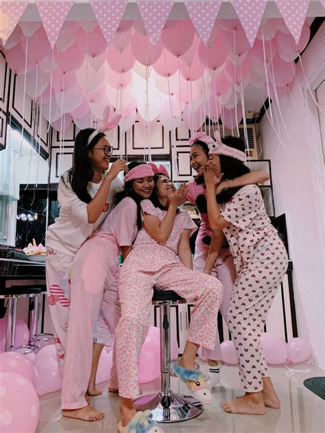 three women in pajamas and pink hats are posing for a photo with balloons hanging from the ceiling