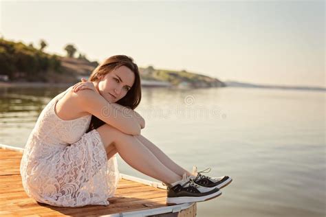 Sad Lonely Young Woman Sitting Hugging Her Knees On The Pier With Sad