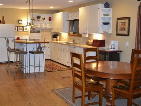 A Kitchen And Dining Room With White Cabinets Wood Floors And An