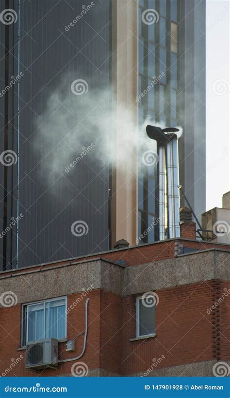 Smoke Rising From A Chimney Of A Building Between Skyscrapers Stock