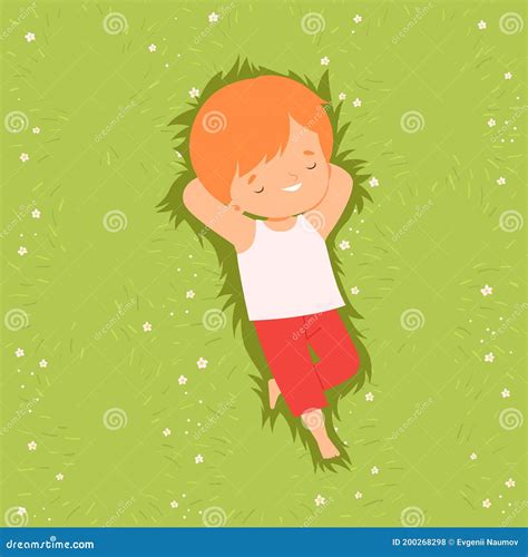 Top View Of Adorable Boy Lying Down On Green Lawn With Hands Behind His