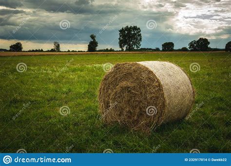 Round Hay Bale In A Green Meadow And Cloudy Sky Stock Photo Image Of