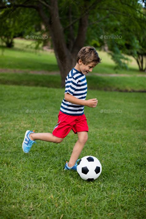 Boy Playing Football In Park Stock Photo By Wavebreakmedia Photodune
