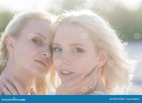 beautiful lesbian couple walking on sand along river bank on their wedding day stock image