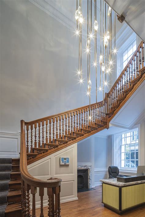 An Elegant Staircase With Chandelier And Seating Area