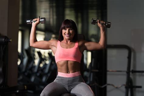 Premium Photo Woman Exercising Shoulders With Dumbbells In The Gym