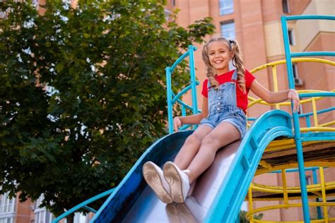 Happy Girl Sliding On A Slide In A Playground Free Photo
