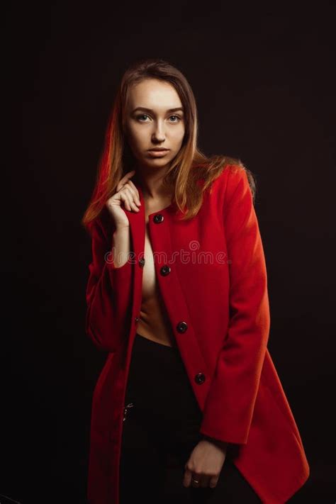 Fashionable Young Woman In Trendy Red Coat Clothed On The Naked Stock