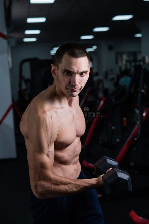 Shirtless Man Doing Bicep Exercises With Dumbbells In The Gym Stock