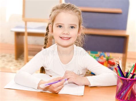 Cute Smiling Little Girl Is Writing At The Desk Stock Photo Image Of