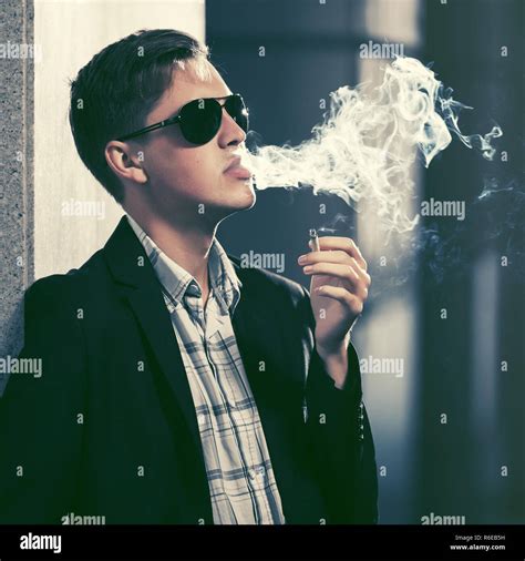 Young Handsome Man In Sunglasses Smoking A Cigarette In City Street