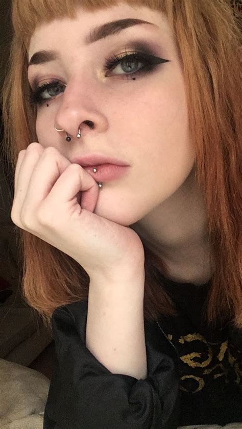 A Woman With Red Hair And Piercings On Her Nose Is Posing For The Camera