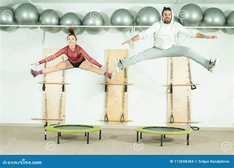 Young Beautiful Fitness Couple Workout Extreme Acrobatic Exercise On Trampoline Jumps As