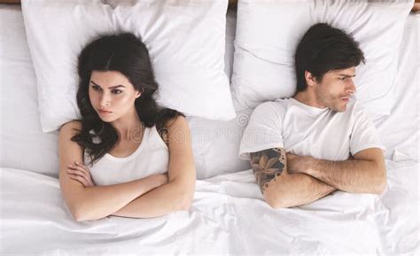 Young Spouses Ignoring Each Other In Bed Lying With Crossed Hands