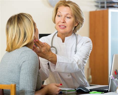 Mature Doctor Checking Lymph Nodes Of Female Patient Stock Photo