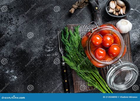 Pickled Cherry Tomatoes In A Glass Jar With Herbs Black Background