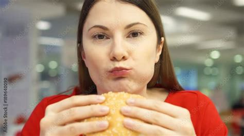 Very Hungry Girl Eating Hamburger On Food Court Woman Biting Cheeseburger At Fast Food