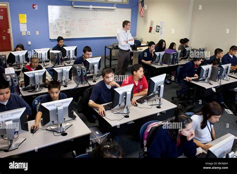 Teacher Monitors High School Students In Computer Lab At Charter School