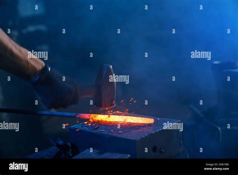 Close Up Of Strong Male Hands And Safety Gloves Forging Molten Metal On