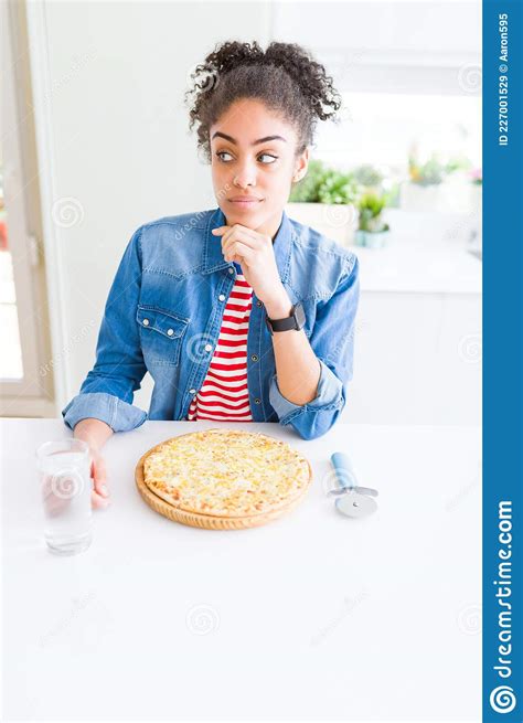 Young African American Woman Eating Homemade Cheese Pizza Serious Face Thinking About Question