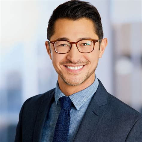 A Man Wearing Glasses And A Suit Smiling