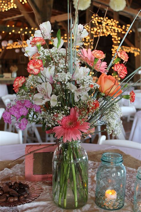 A Vase Filled With Lots Of Flowers On Top Of A Table Next To A Candle