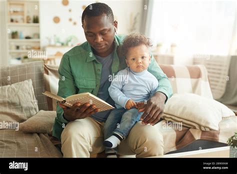 Portrait Of Mature African American Man Reading Book To Child Sitting