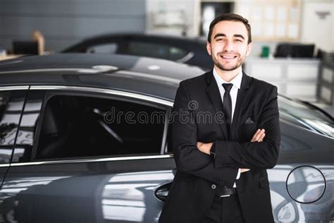 Handsome Young Classic Car Salesman Standing At The Dealership Stock
