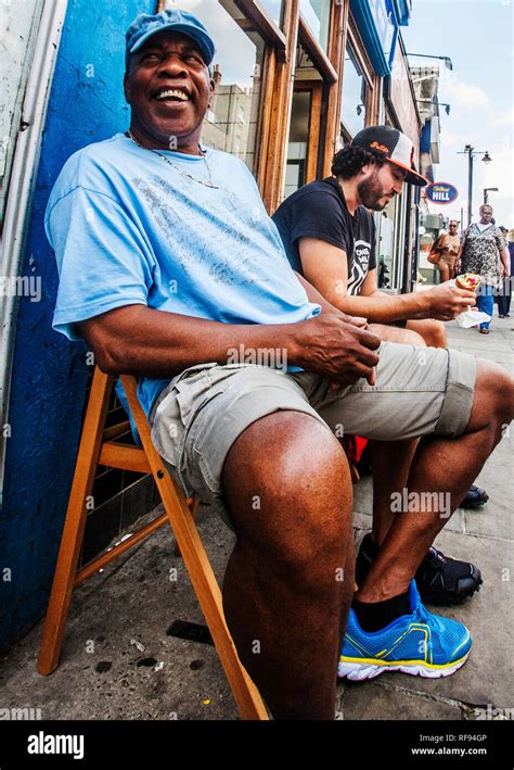 Black Man Seated In Shorts And Baseball Hat Hi Res Stock Photography