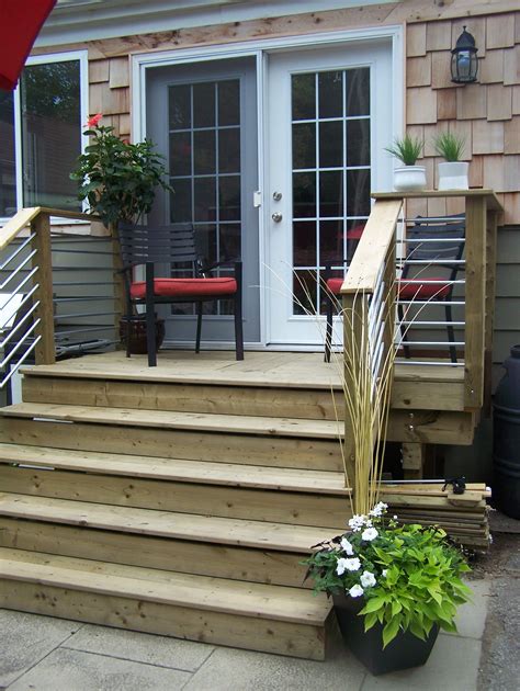 A Wooden Deck With Steps Leading Up To A Door And Patio Furniture In