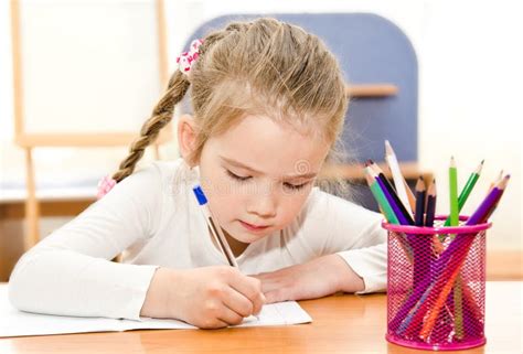 La Petite Fille écrit Au Bureau Dans Lécole Maternelle Image Stock
