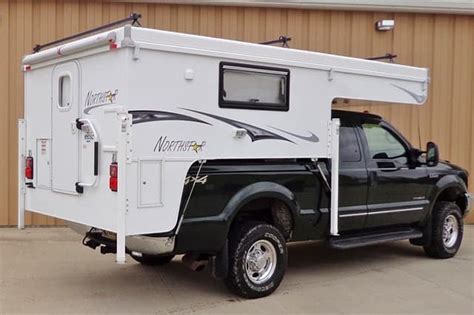 A Truck With A Camper Attached To Its Bed Parked In Front Of A Building