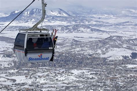 A Ski Lift With Skiers Going Up The Mountain In Its Cable Car