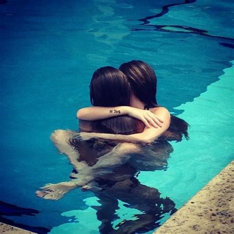 Two People Are Hugging In The Water Near A Swimming Pool With Their Arms Around Each Other